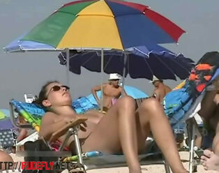 Big-titted lady sunbathing in a bare beach