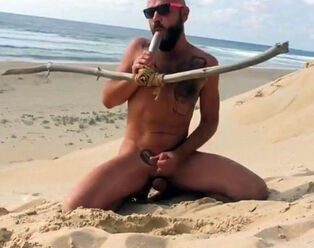 dude pokes himself on the beach with a wooden